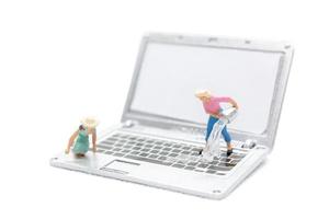 Miniature people cleaning laptop computer on white background photo