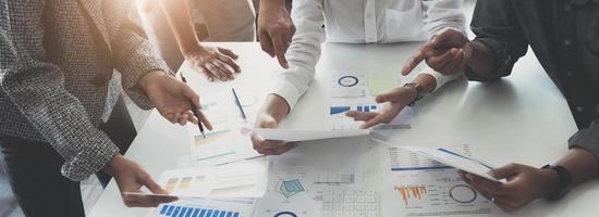 Close up top view of diverse businesspeople cooperate work together discussing company financial statistics, multiracial colleagues employees collaborate brainstorm with finance document at meeting photo