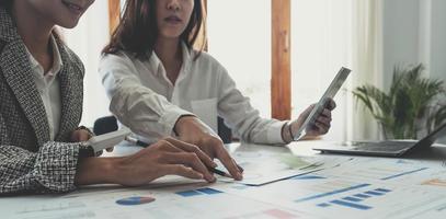 dos jóvenes empresarias asiáticas discuten el trabajo del proyecto de inversión y la estrategia de planificación. gente de negocios hablando junto con una computadora portátil en la oficina. foto