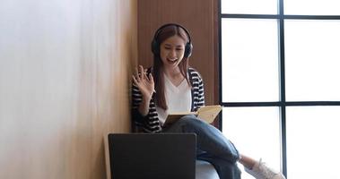 Asian woman wearing headphones study online watching webinar podcast on laptop listening learning education course conference calling, elearning concept. photo