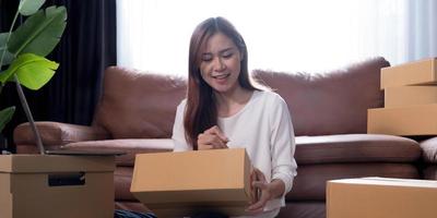 Envío de compras en línea, joven emprendedor de pequeña empresa escribiendo la dirección en una caja de cartón en el lugar de trabajo. foto