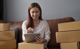 Starting small businesses SME owners female entrepreneurs Use a laptop or notebook to receive and review orders online to prepare to pack boxes, sell to customers, SME online business ideas. photo