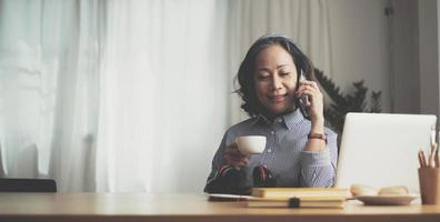 Happy pretty mature woman speaking on mobile phone portrait. Senior grey haired lady making telephone call, sitting on couch at home, enjoying talk, communication photo