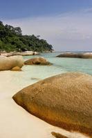 Rocks on white sand beach. photo