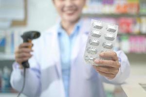 Farmacéutica femenina escaneando código de barras en una caja de medicamentos en una farmacia moderna. foto