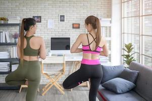 mujeres amigas jóvenes en forma haciendo yoga y meditación en casa, deporte y concepto de estilo de vida saludable. foto