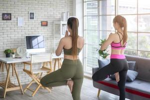 mujeres amigas jóvenes en forma haciendo yoga y meditación en casa, deporte y concepto de estilo de vida saludable. foto