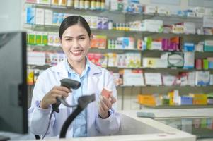 Farmacéutica femenina escaneando código de barras en una caja de medicamentos en una farmacia moderna. foto