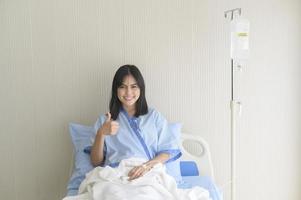 paciente joven esperanzada y feliz en el hospital, la atención médica y el concepto médico foto