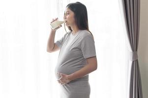 Young pregnant woman drinking milk at home, healthcare and pregnancy care photo