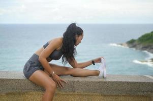 una hermosa mujer en forma en ropa deportiva haciendo ejercicio en el pico de la montaña junto al mar, concepto de salud y viaje. foto