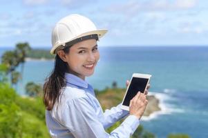 Female engineer working on the seaside wearing a protective helmet photo