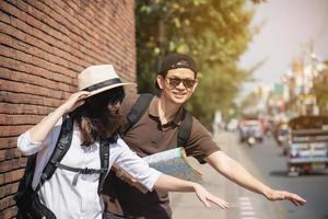 Asian backpack couple tourist holding city map crossing the road - travel people vacation lifestyle concept photo