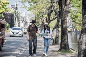 Asian backpack couple tourist holding city map crossing the road - travel people vacation lifestyle concept photo