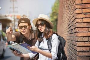 Asian backpack couple tourist holding city map crossing the road - travel people vacation lifestyle concept photo