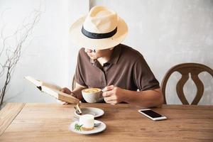 Relax Asian man drink coffee and read book in a modern style coffee shop - people with coffee cup easy lifestyle concept photo