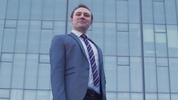 Confident businessman looking at camera. Confident and successful young businessman looking at camera in front of luxury business building. video