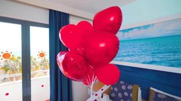 concetto di camera d'albergo per la luna di miele. camera decorata con petali di rosa. palloncini rossi. concetto romantico di camera d'albergo. video