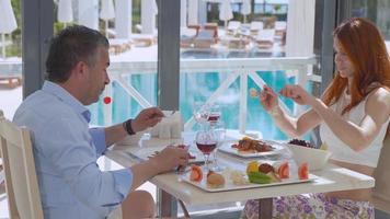 jeune couple romantique en train de manger. bon appétit. vin et viande rouge. belle conversation agréable. video