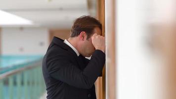 Businessman punching the wall in sadness. Businessman receiving negative news punches the wall, leans his head against the wall. He sighs. video