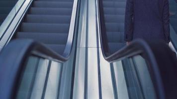 homme d'affaires avec sac qui monte l'escalator. homme d'affaires avec mallette devant un immeuble d'affaires de luxe monte l'escalator. image d'un bâtiment moderne et d'un homme d'affaires moderne. video