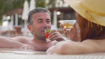 Drinking by the pool. Couples who spend pleasant moments in the pool are drinking drinks. Alcoholic beverage. video