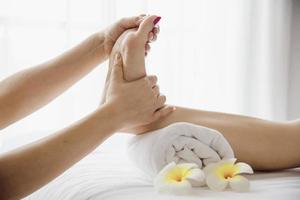 mujer que recibe un servicio de masaje de pies de masajista cerca de la mano y el pie - relájese en el concepto de servicio de terapia de masaje de pies foto