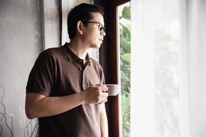 Relax Asian man drink coffee and read book in a modern style coffee shop - people with coffee cup easy lifestyle concept photo