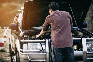 el hombre trata de arreglar un problema de motor de automóvil en una carretera local chiang mai tailandia - personas con concepto de transporte de problemas de automóvil