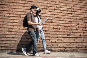 Asian backpack couple tourist holding city map crossing the road - travel people vacation lifestyle concept photo