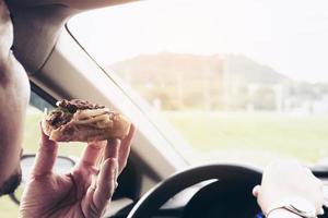 Business man eating pizza while driving a car dangerously