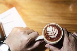 hombre que sostiene la taza de café y la tarjeta de embarque esperando el vuelo en avión para el trabajo de negocios foto