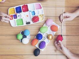 gente pintando coloridos huevos de pascua - concepto de celebración de vacaciones de pascua foto