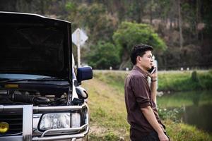 Man try to fix a car engine problem on a local road Chiang mai Thailand - people with car problem transportation concept photo