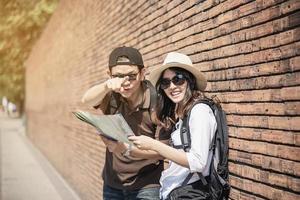 Asian backpack couple tourist holding city map crossing the road - travel people vacation lifestyle concept photo