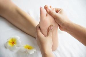 mujer que recibe un servicio de masaje de pies de masajista cerca de la mano y el pie - relájese en el concepto de servicio de terapia de masaje de pies
