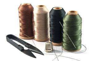 Thimble,needles,spools and scissors for sewing on a background thread photo