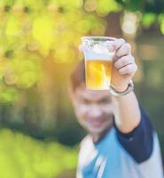 Celebration beer cheers concept - close up hand holding up glasses of beer of young man in outdoor party during his victory competition or successful task meeting photo