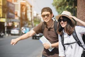 mochila asiática pareja turista sosteniendo un mapa de la ciudad cruzando la carretera - gente de viaje concepto de estilo de vida de vacaciones foto