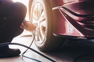 el técnico está inflando el neumático del automóvil - concepto de seguridad del transporte del servicio de mantenimiento del automóvil foto