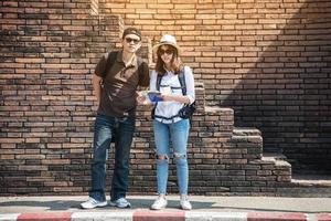 Asian backpack couple tourist holding city map crossing the road - travel people vacation lifestyle concept photo