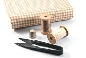 Thimble,needles,spools and scissors for sewing on a background thread photo