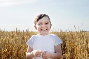 Cute boy walking across the wheat field, making funny faces photo