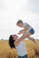 feliz familia de madre y niño pequeño caminando en el campo de trigo foto