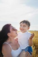 Happy family of mother and infant child walking on wheat field photo