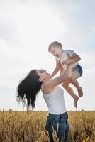 feliz familia de madre y niño pequeño caminando en el campo de trigo foto