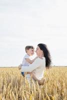Happy family of mother and infant child walking on wheat field, family portrait photo
