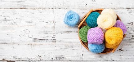 bright colorful yarn wool in a basket on wooden background photo