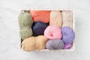 pastel colored yarn wool in a white basket on marble background photo