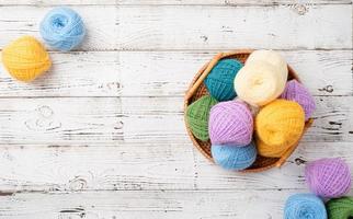 lana de hilo de colores brillantes en una cesta sobre fondo de madera foto